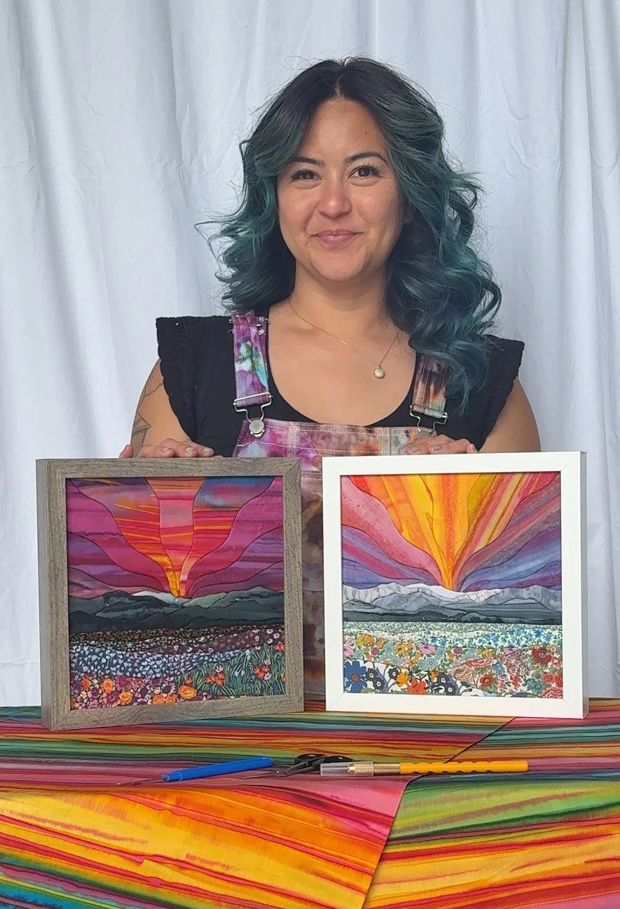 Hannah Austin of Needle OR Thread holding two finished kinusaiga sunrise landscapes
